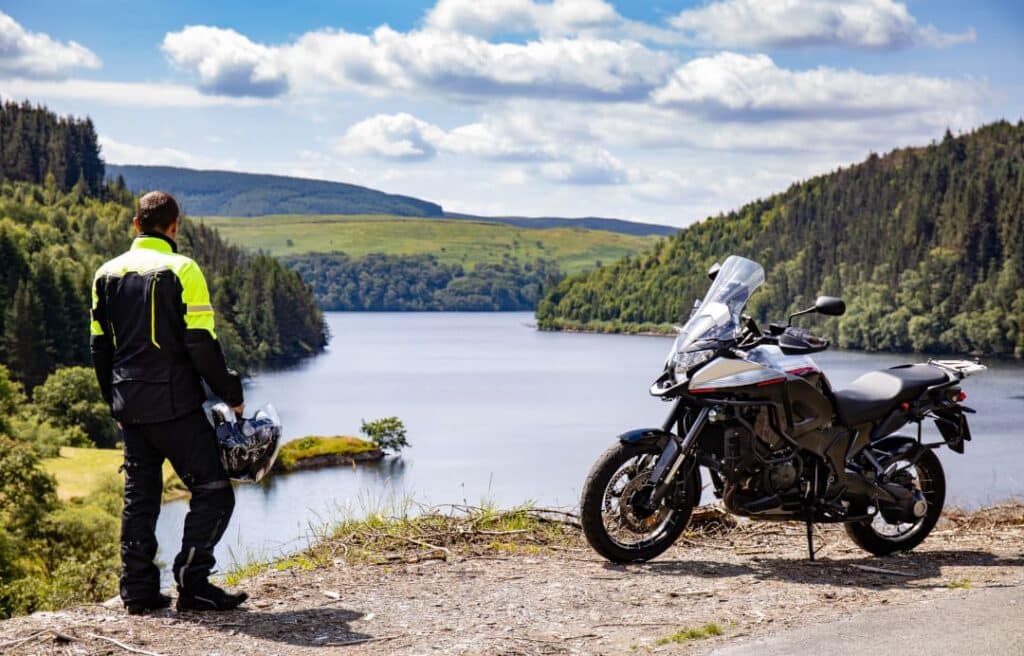 Sicherheit – Biker mit Schutzkleidung und Motorrad an sicherem Aussichtspunkt