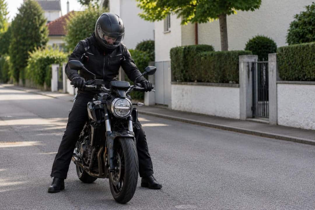 Motorradfahrer mit Schutzkleidung hat sein Motorrad beim Anfahren abgewürgt